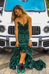 a woman in a green dress posing in front of a mercedes benz